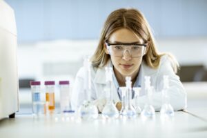 Female medical or scientific researcher looking at a flasks with solutions in a laboratory